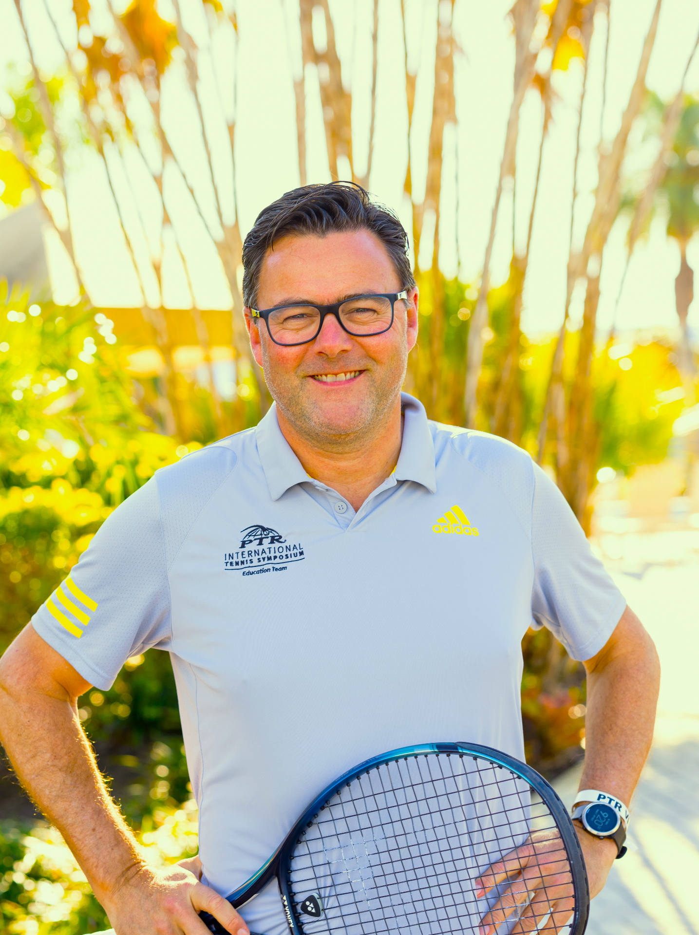 Carl Maes in PTR International Tennis Symposium polo holding a racket
